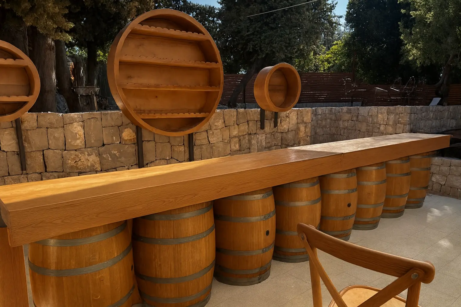 An outdoor bar counter built on a row of barrels, under trees.