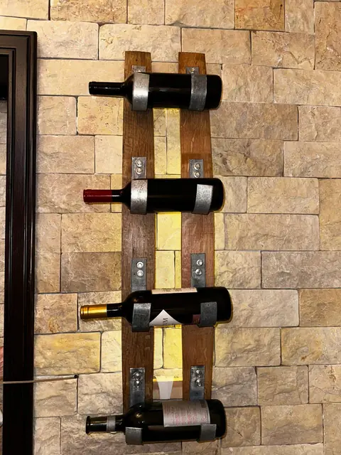 An oak wall wine rack mounted on a stone wall beside a doorway.